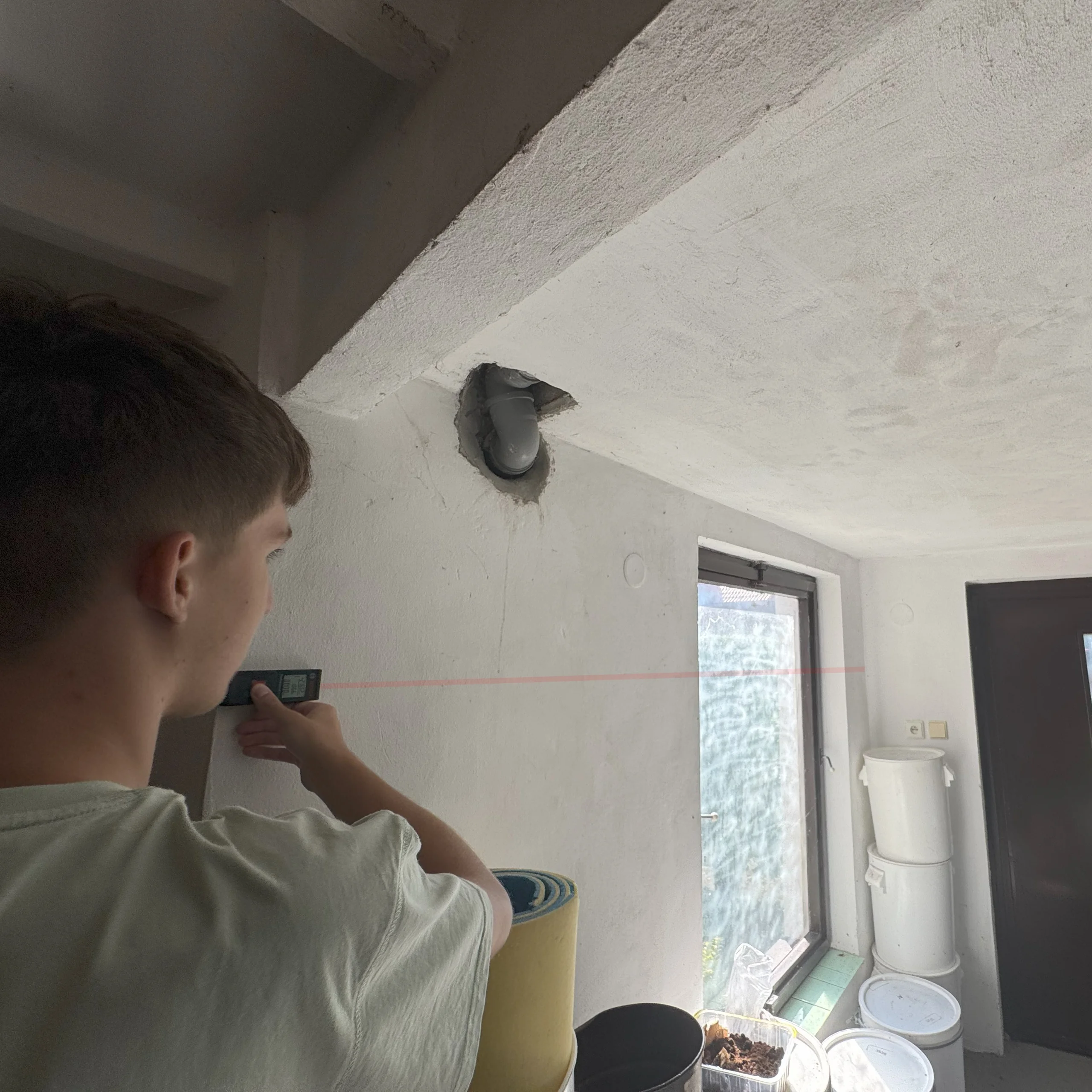 Muž zaměřuje zeď laserem při pasportizaci budovy